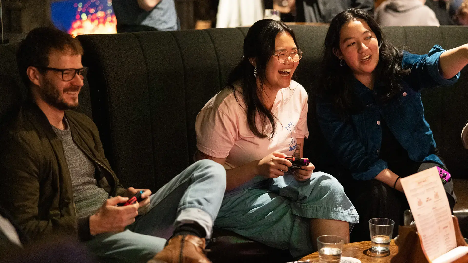 3 friends enjoying drinks and food while playing consoles at Fortress