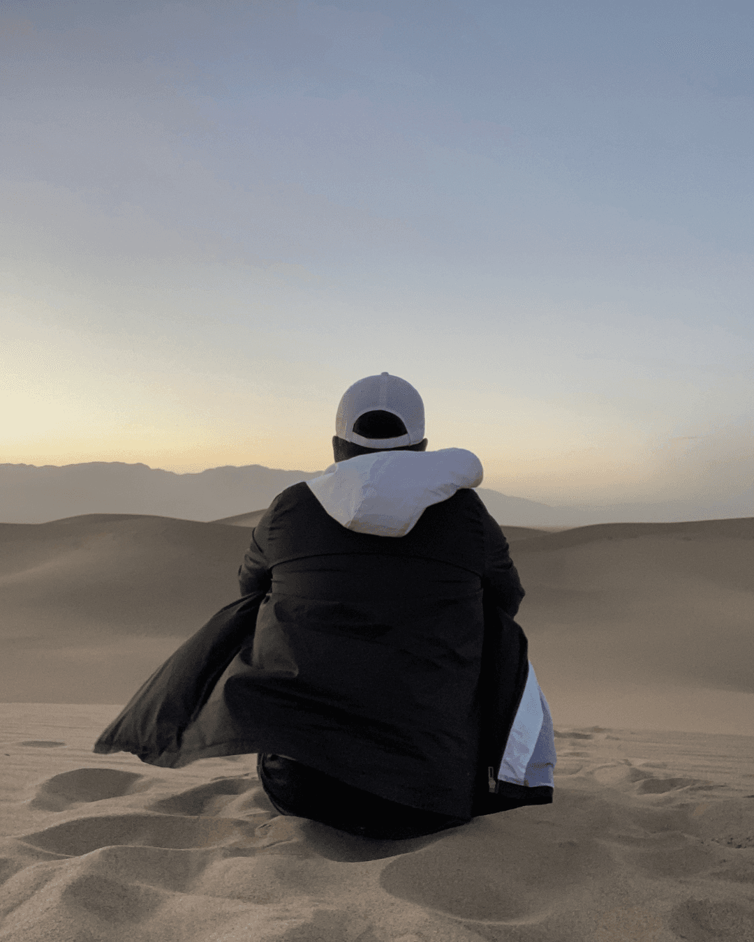 Smiling female therapist with short gray hair, wearing a brown top and a purple shawl, surrounded by a cozy background.
