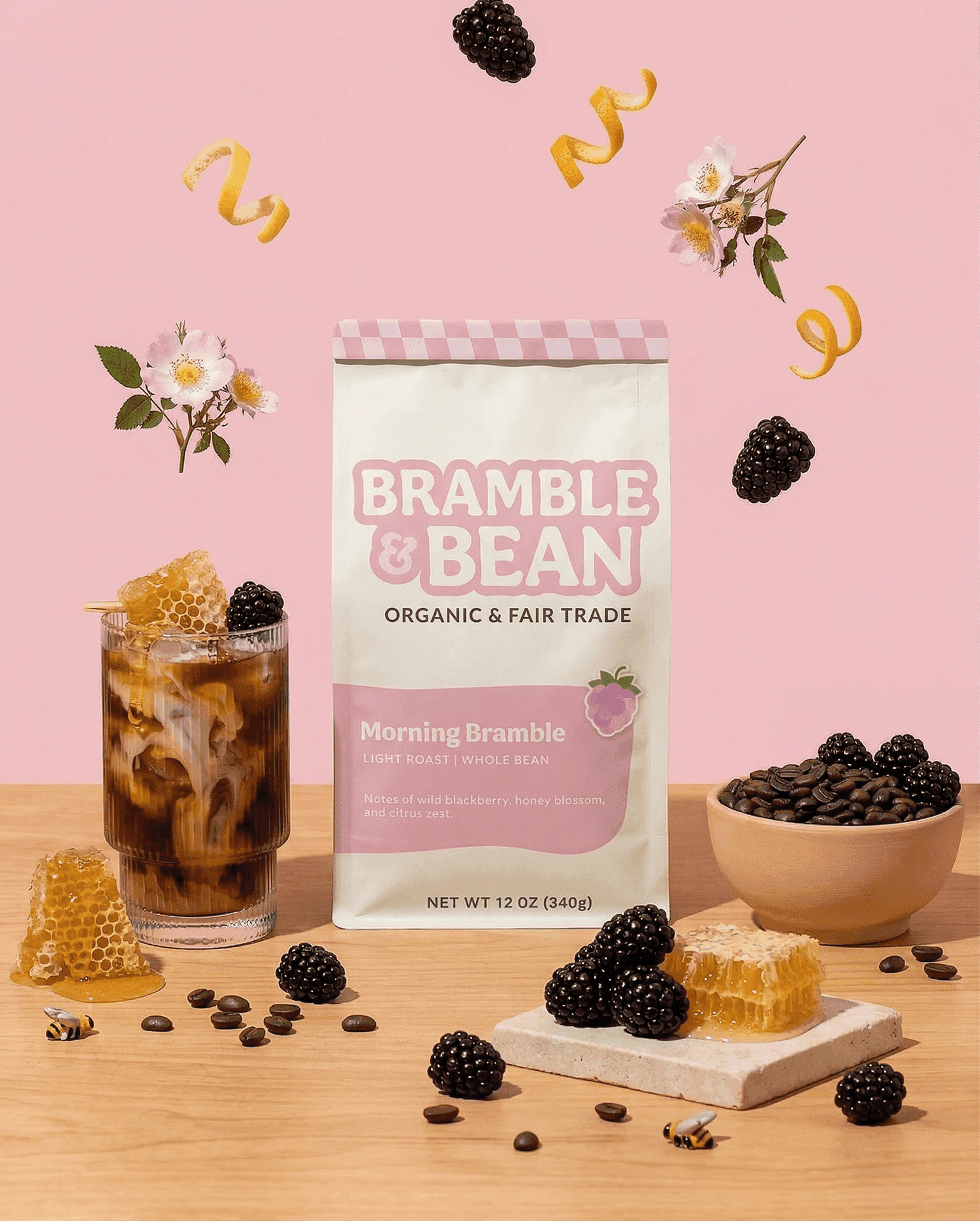 Bramble & bean coffee packaging surrounded by a bowl of coffee beans and an iced coffee.