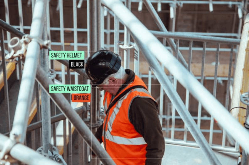 AI-based safety compliance system identifying protective gear and signage on a construction worker at an industrial site