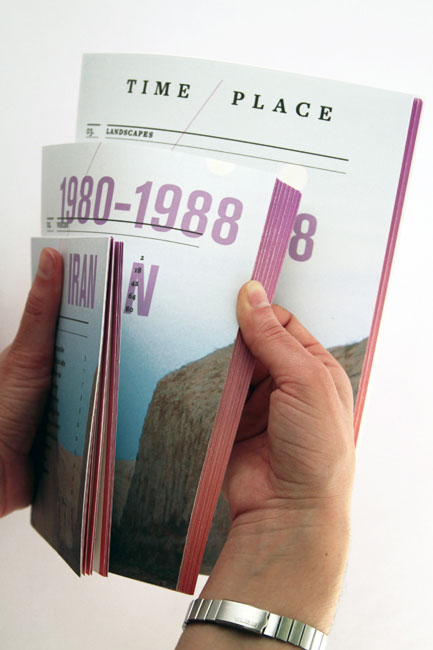 Two hands hold open a magazine titled “Time Place,” displaying the years 1980-1988. The left page shows a landscape image, while the right page features “IRAN” written vertically. A silver watch is visible on the wrist holding the magazine.