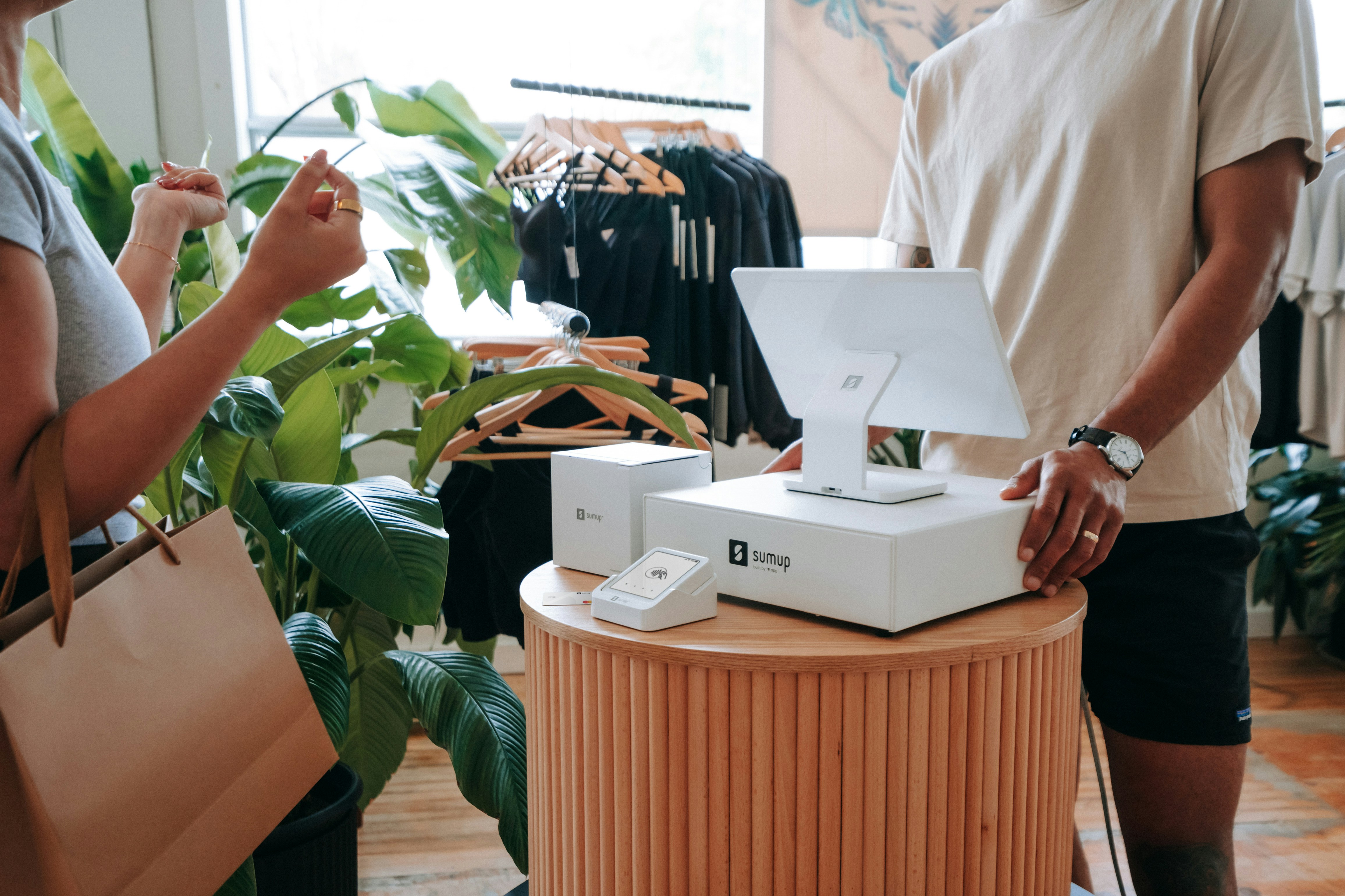 A paper bag in hand and the SumUp Solo on the counter — this photo captures the simplicity of modern payments in a boutique retail store. Ideal for entrepreneurs focused on experience and design.
