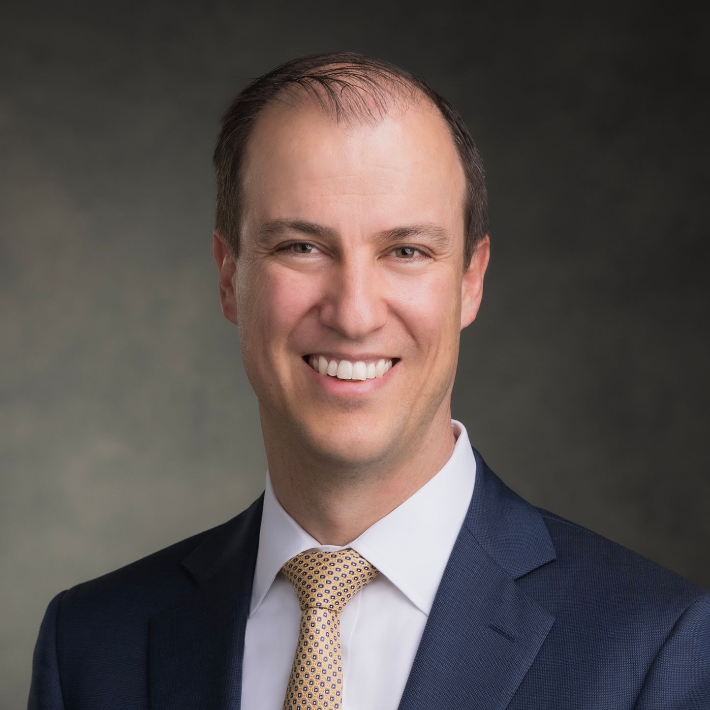 a man with his arms crossed standing in front of a desk