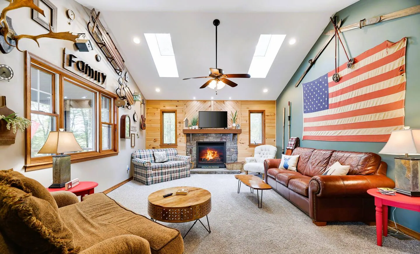 Vaulted family room with stone fireplace, leather sofa and American flag decor at Laketop Lodge