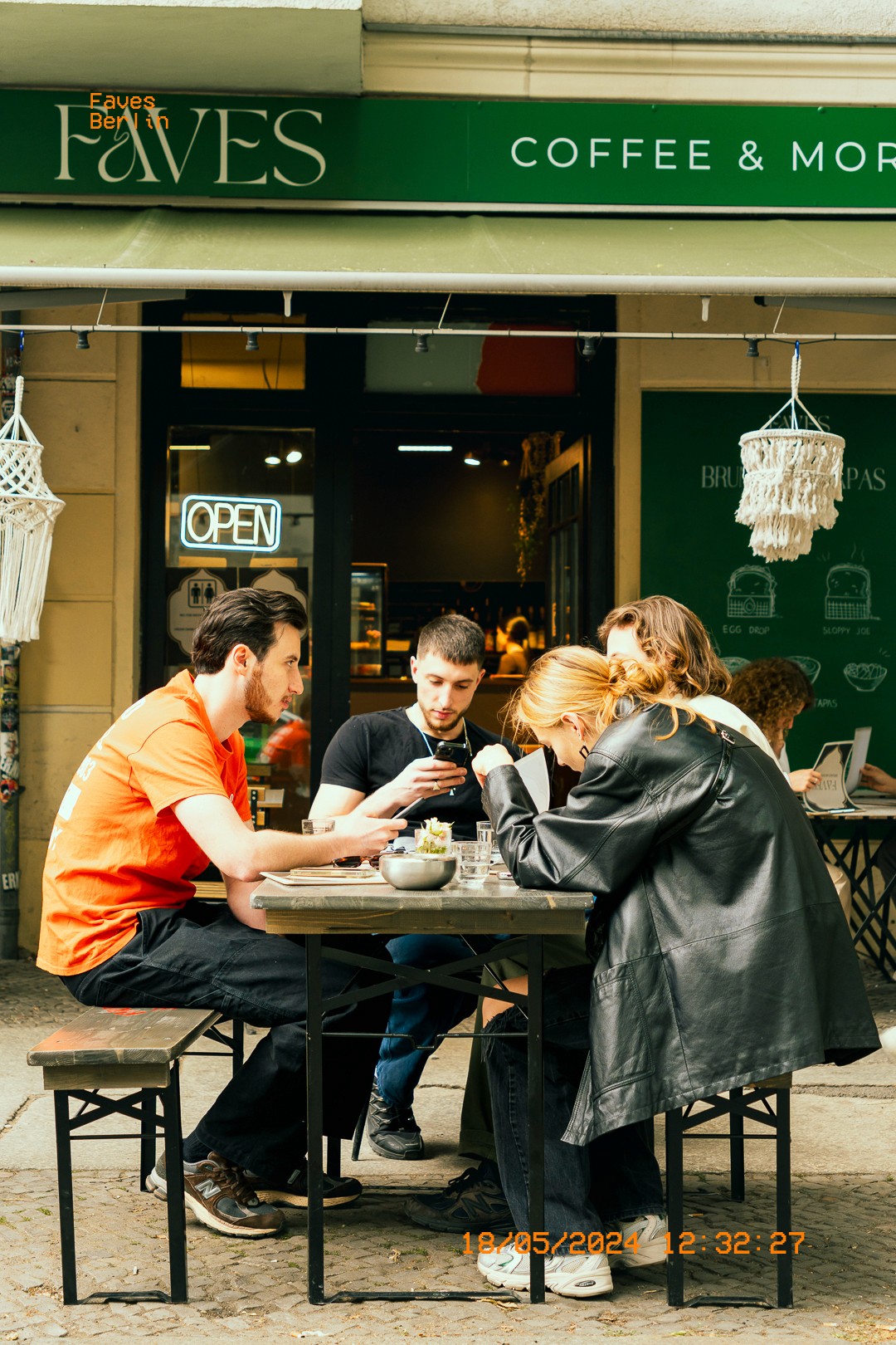 Groupe d'amis partageant un moment au café FAVES à Berlin, en terrasse.
