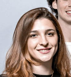 A smiling young woman with warm brown hair and a bright expression, part of the dynamic PointOne team creating digital.