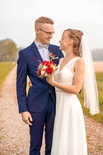 Brautpaar steht sich gegenüber und lächelt während Hochzeitsshooting im Freien in Rosenheim