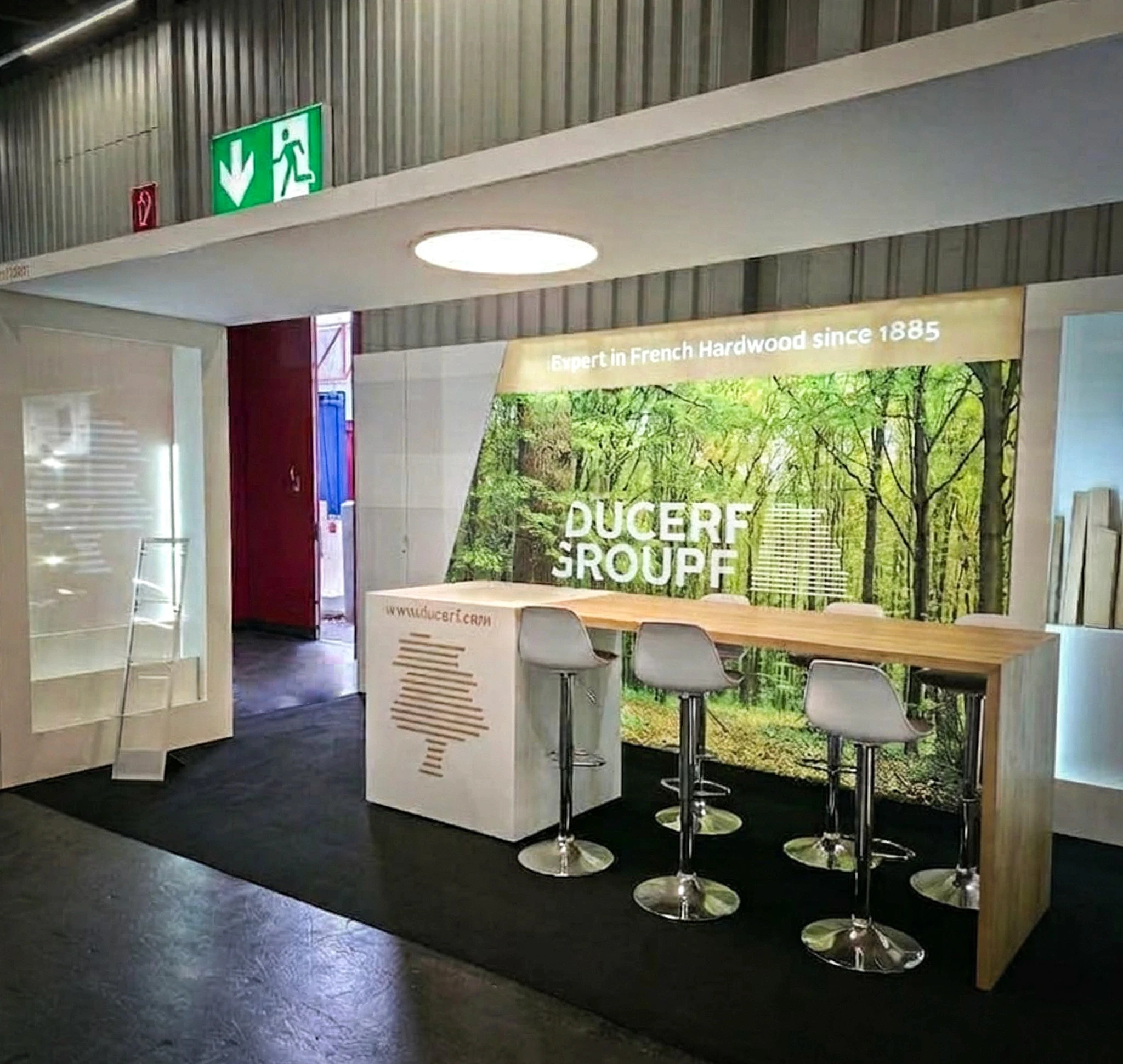 Stand Ducerf Groupe bois feuillus français conçu par EXPACE au Carrefour International du Bois (CIB) 2026 — visuel forestier, comptoir en bois massif et échantillons d'essences rétroéclairés