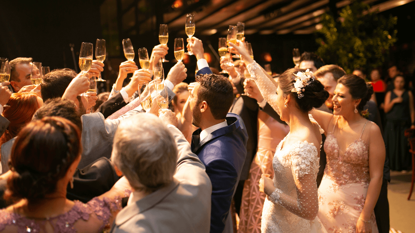 A lively crowd at a celebration, raising their hands in excitement, dressed in formal attire.