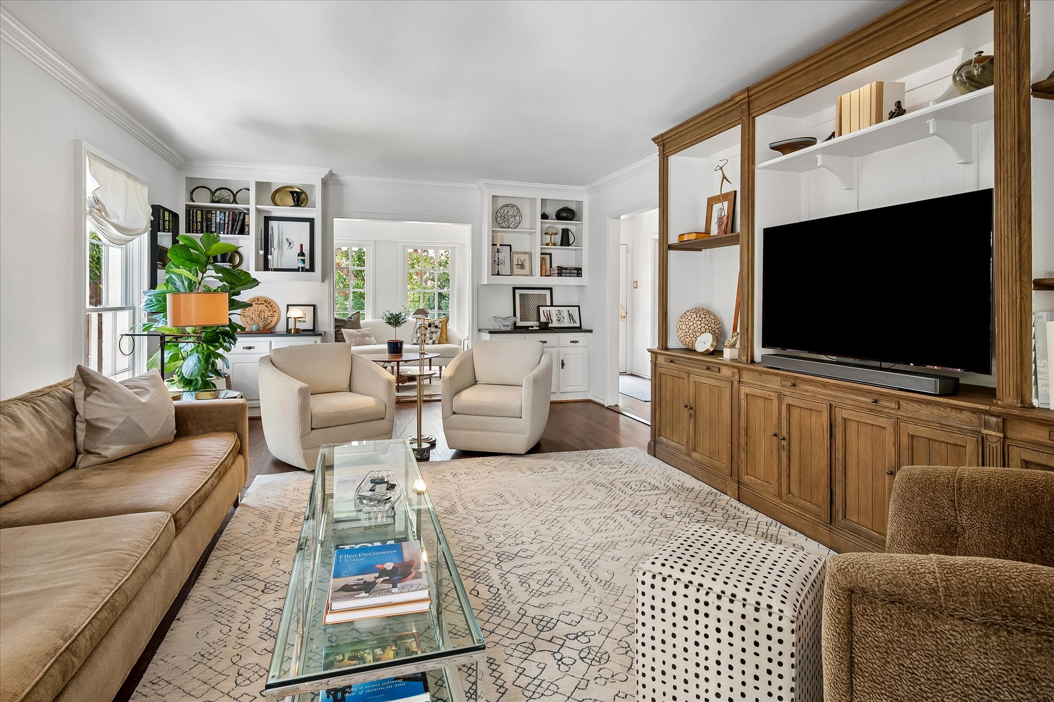 Reverse view of the formal living room with sofa, glass coffee table, fireplace, and full-height wood media cabinetry at 5401 W Mockingbird Lane.