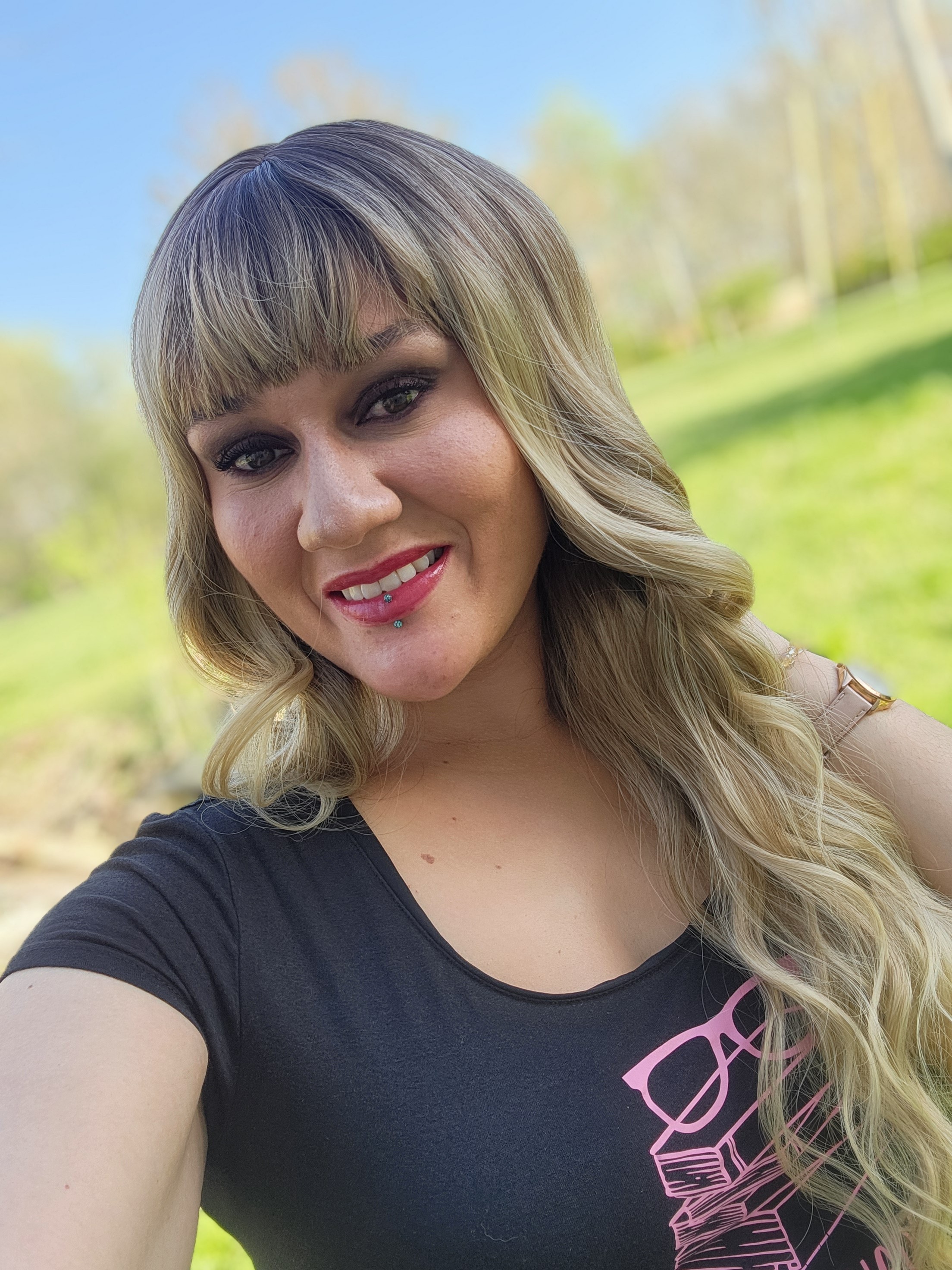 A young person with long, wavy hair sits in front of a plain background, looking directly at the camera.