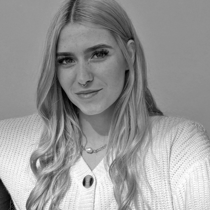 A thoughtful young person with dark hair gazes to the side, captured in soft black and white lighting.