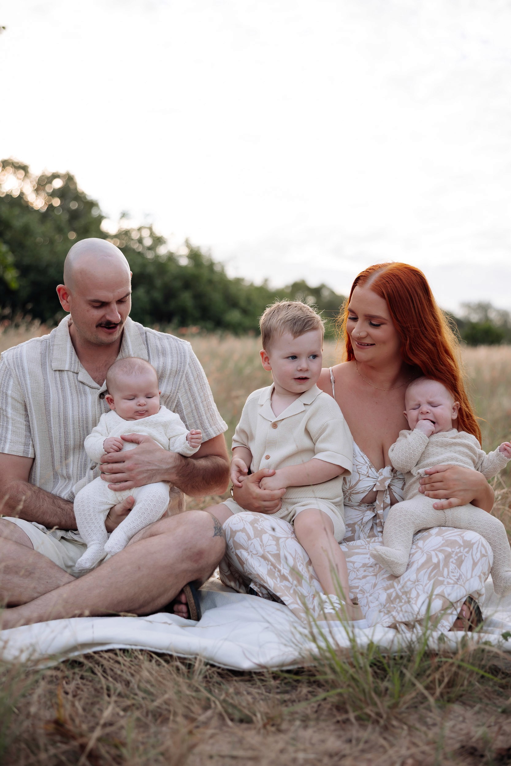 Parents sitting in the grass with children in family photo Mackay