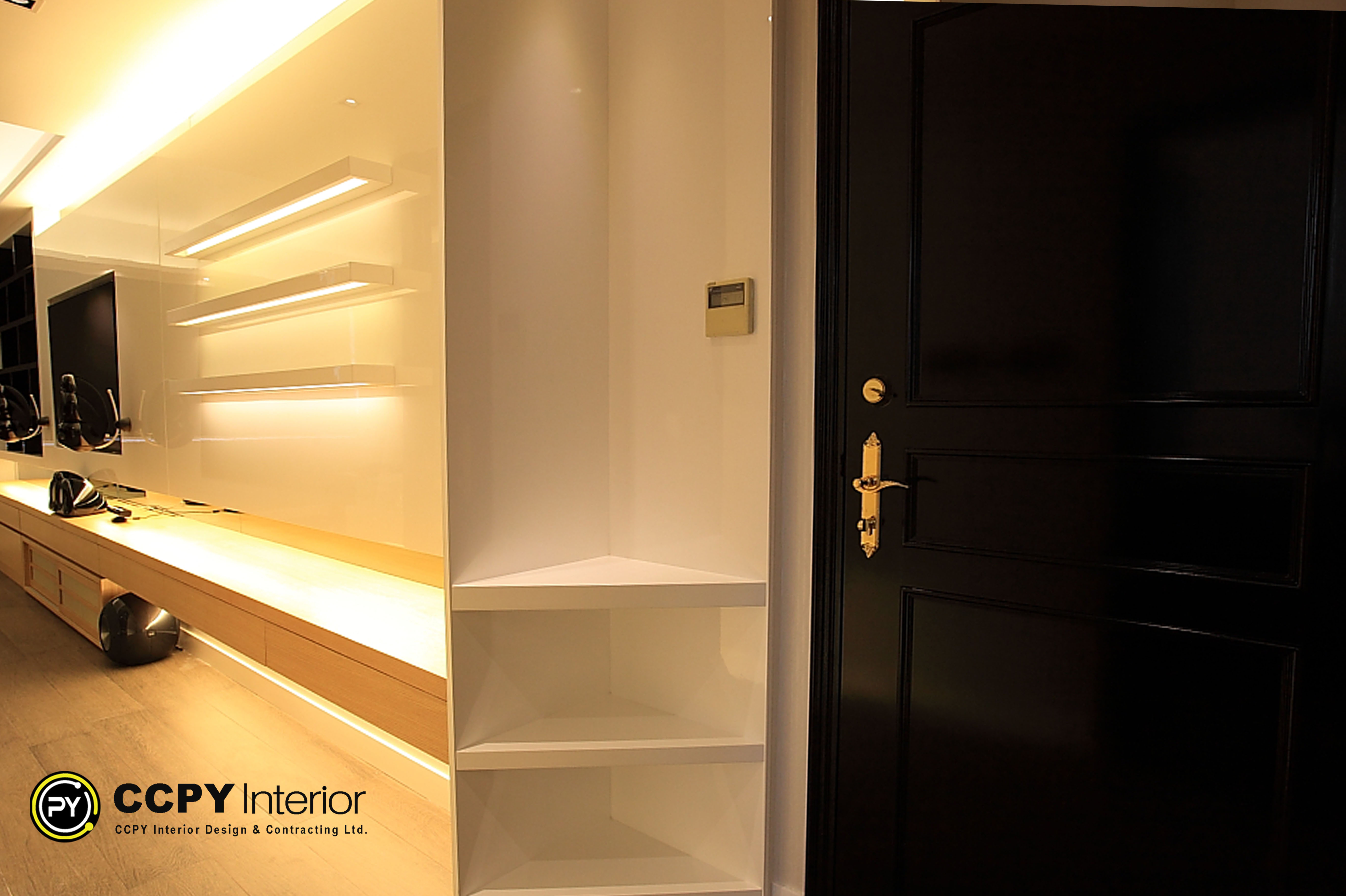 Entryway detail at Standalone House, Perkins Road featuring a black lacquered door with brass hardware and custom white corner shelving for functional storage.