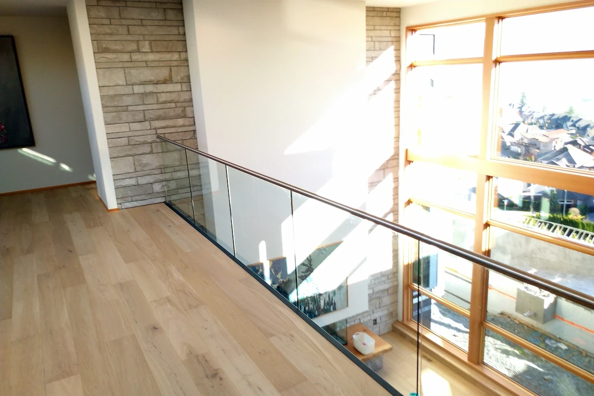 A loft style second storey with a frameless glass railing.