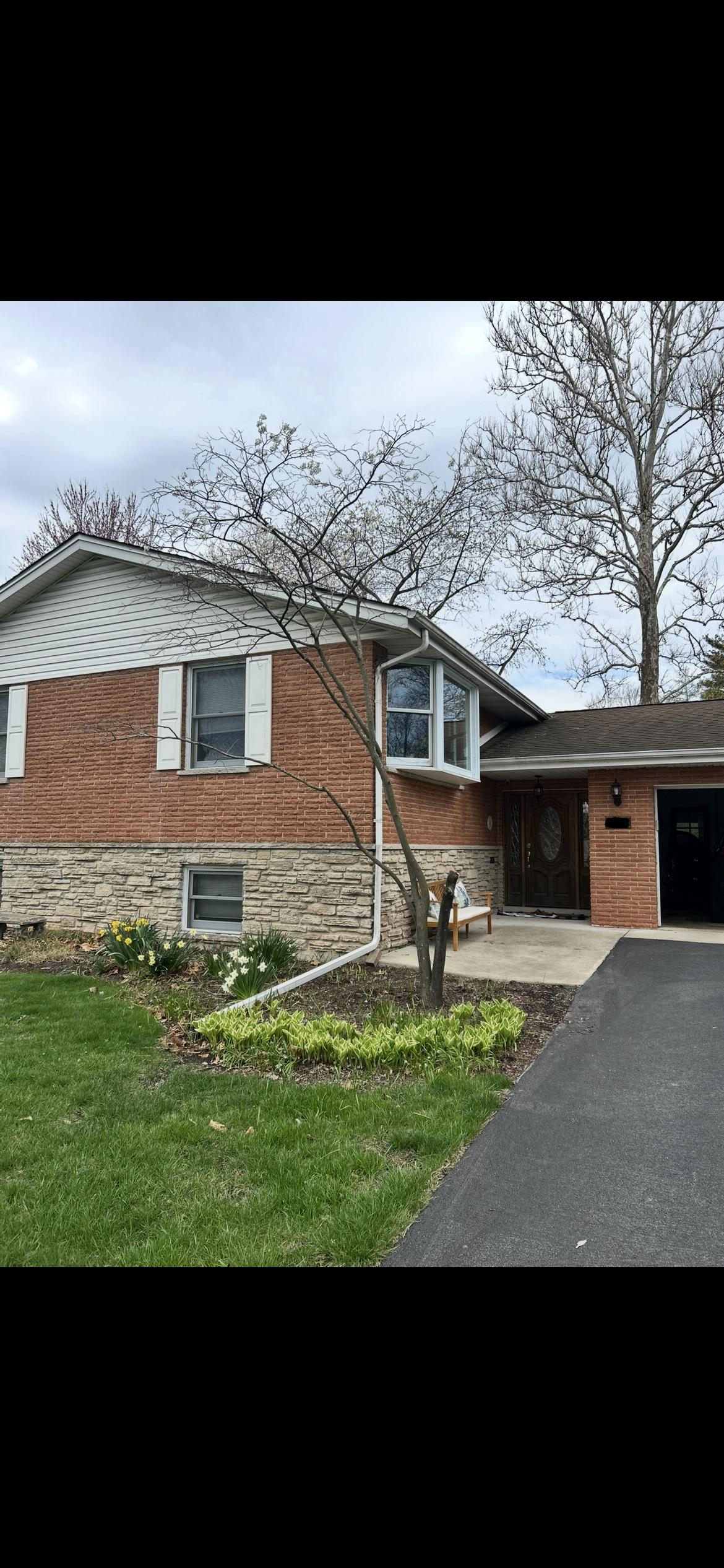 Brick house exterior before update — red brick split-level with white vinyl siding and white shutters