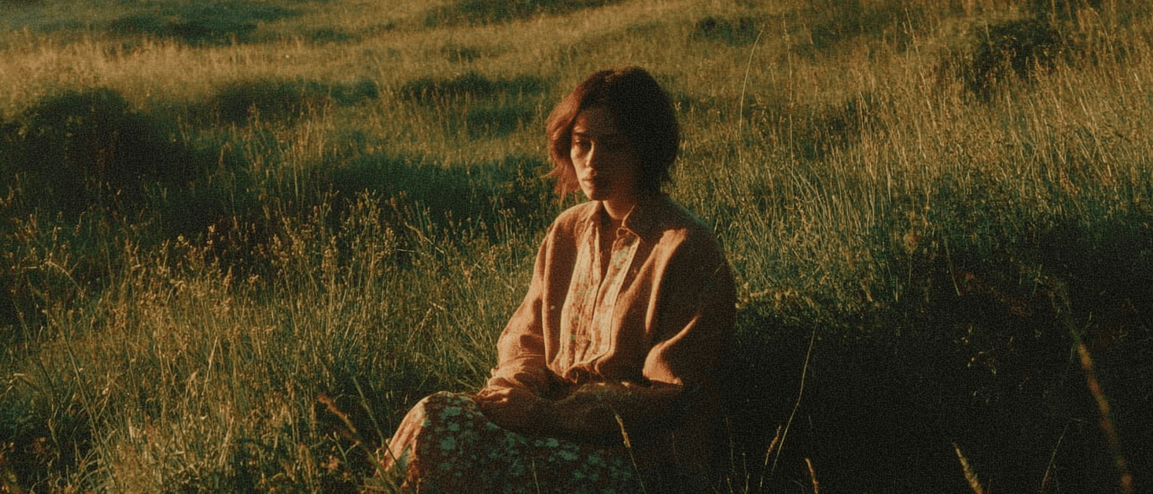 Image of a person sitting in the green fields