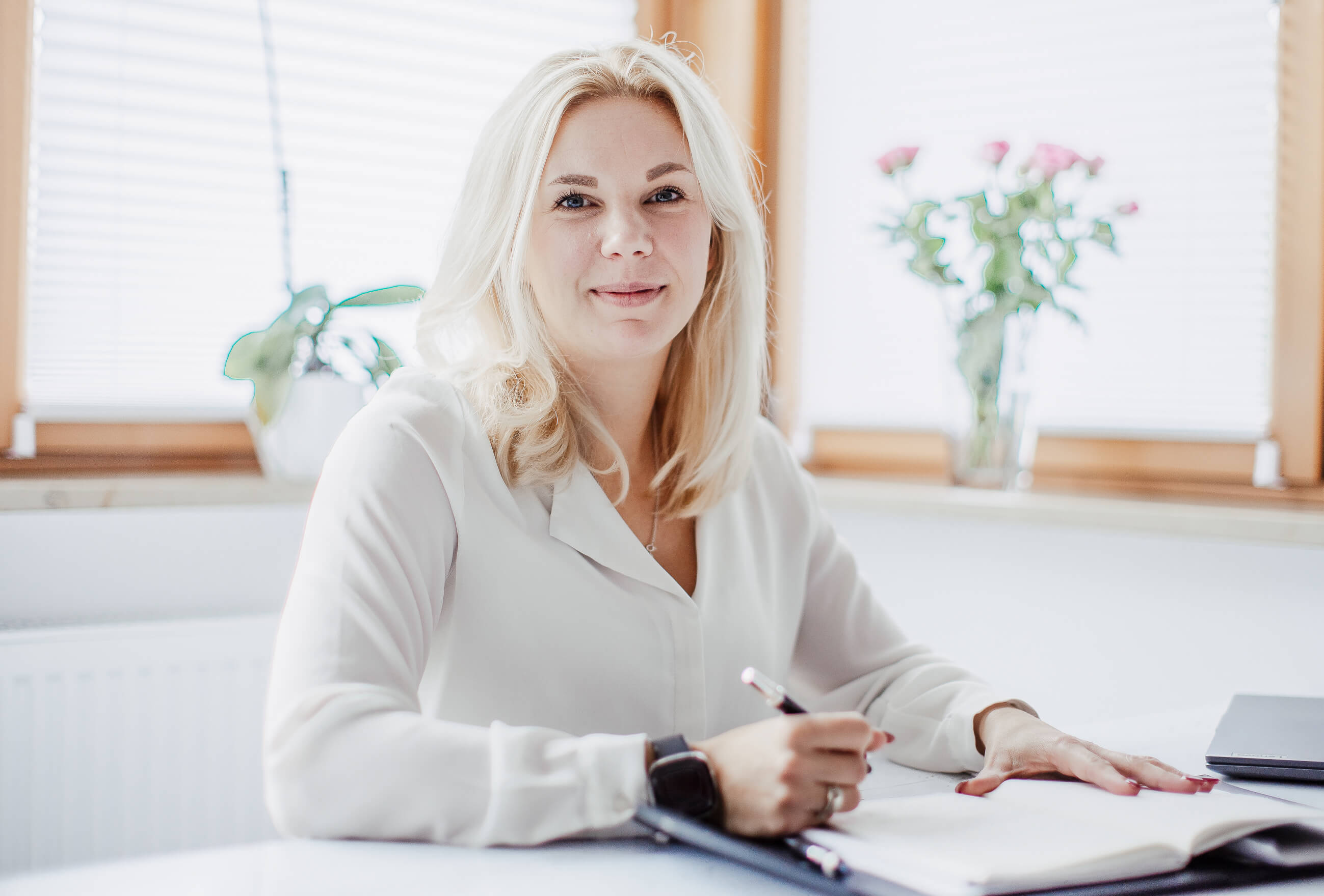 Theresa an ihrem Schreibtisch bei der Arbeit an HR-Copywriting-Strategie, umgeben von Pflanzen in einem hellen professionellen Workspace