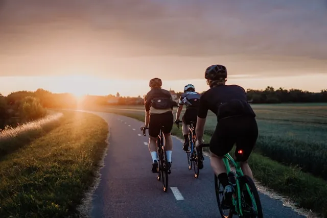 Cyclists riding together on a road at sunset during a training session