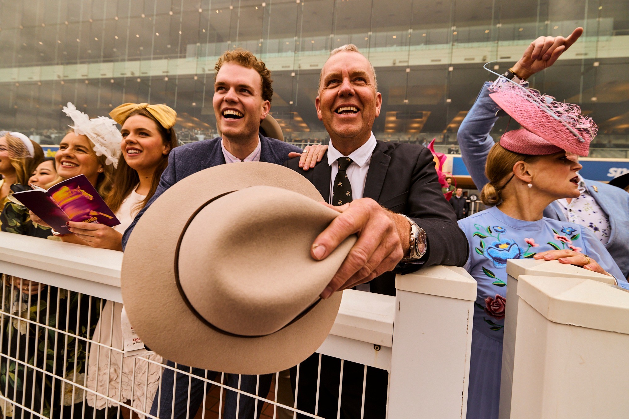 A woman with red hair wears a lavender coat and a white sweater, accessorized with a gray scarf. She has a calm expression against a neutral background.