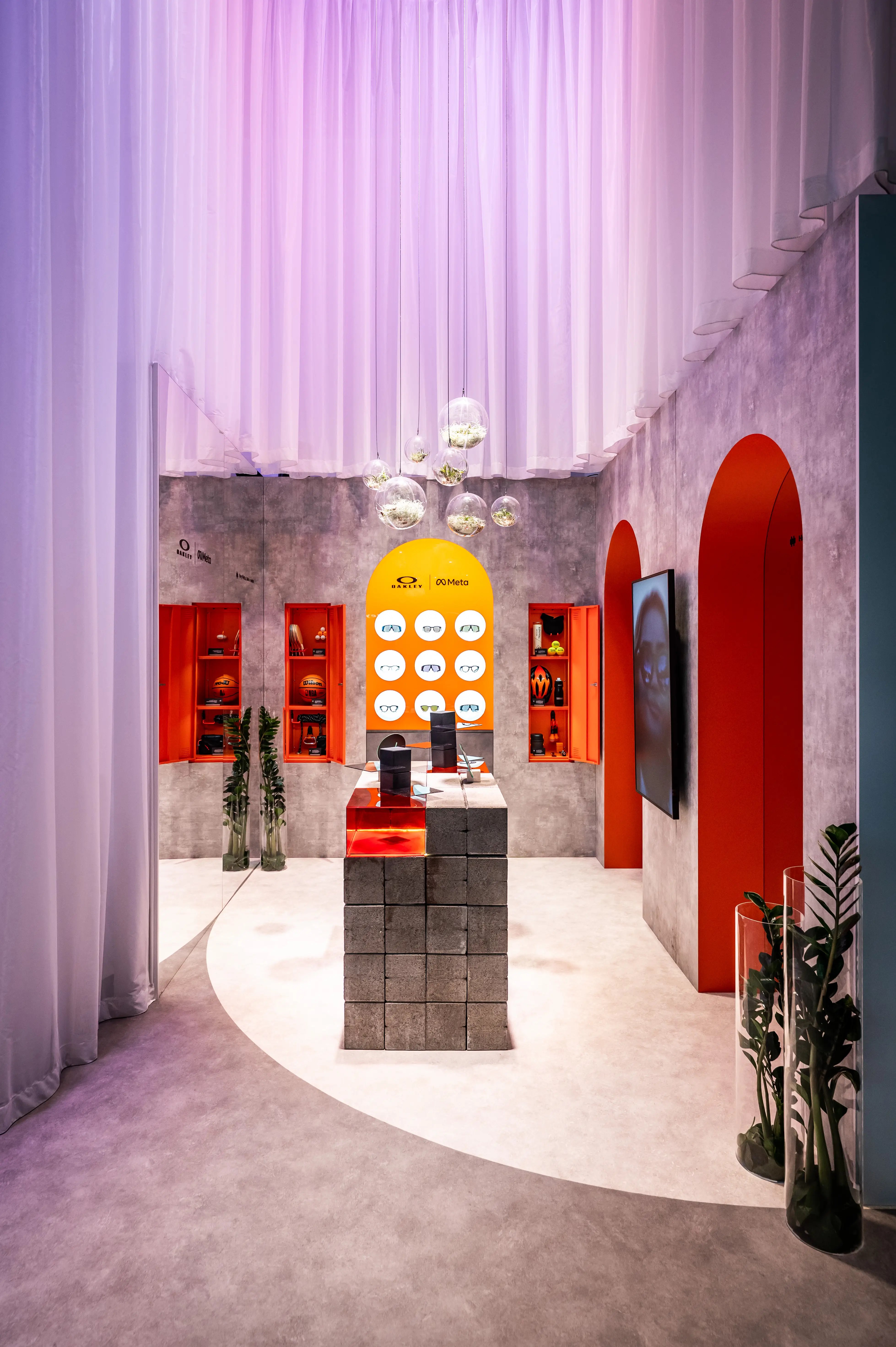 Oakley zone with concrete-look walls, orange arched niches and brick display table under glass spheres.