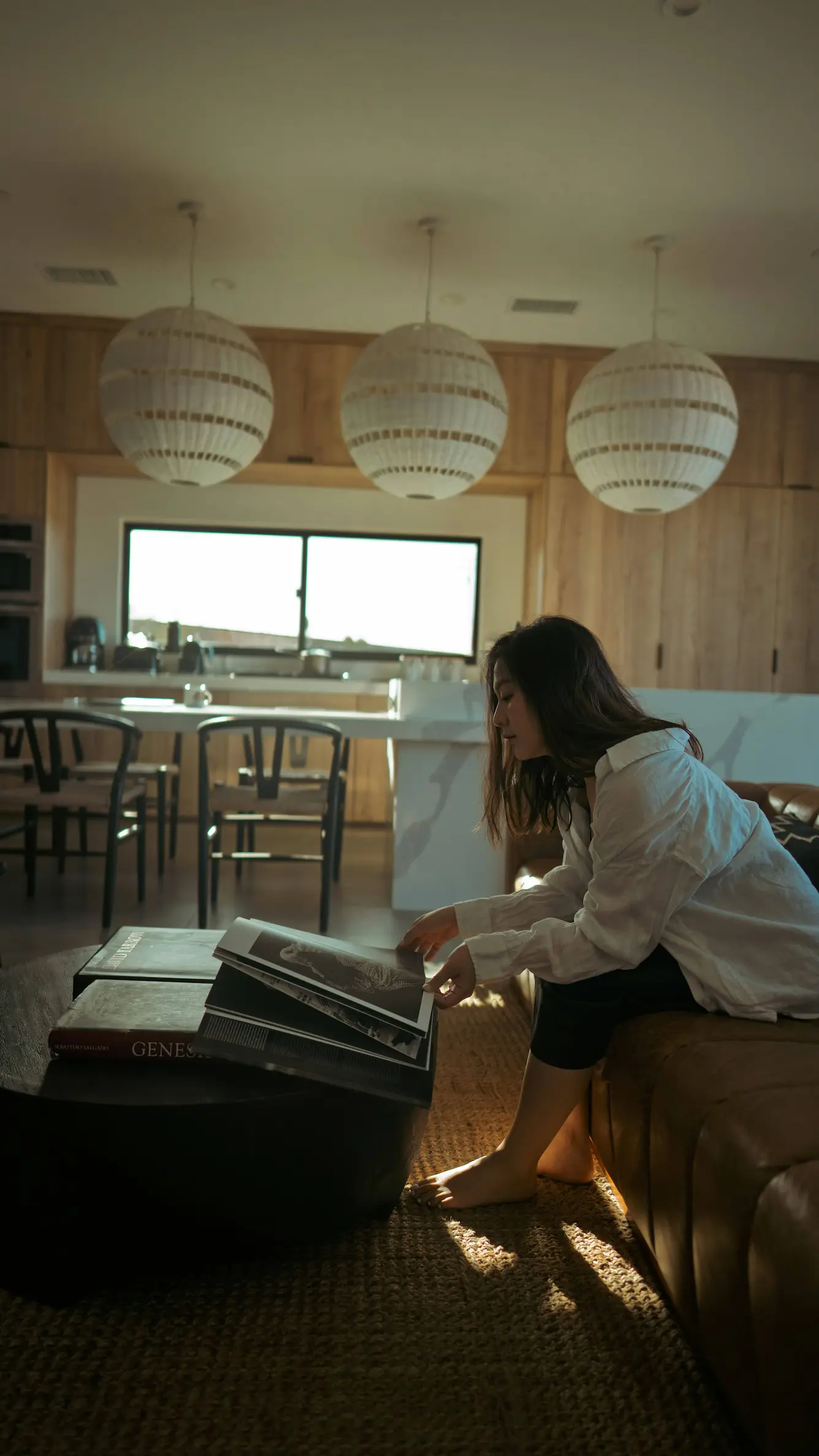 A woman sitting on a sofa in the kitchen, yellow sunlight coming through the window