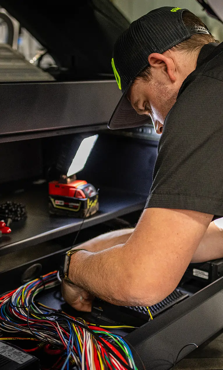 Technician working on the wiring inside a vehicle during an upfit