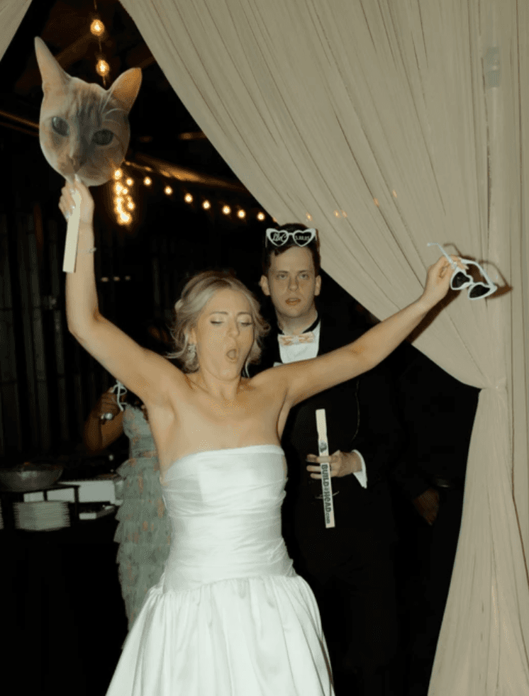 Groom lifting the bride while dancing among cheering wedding guests.