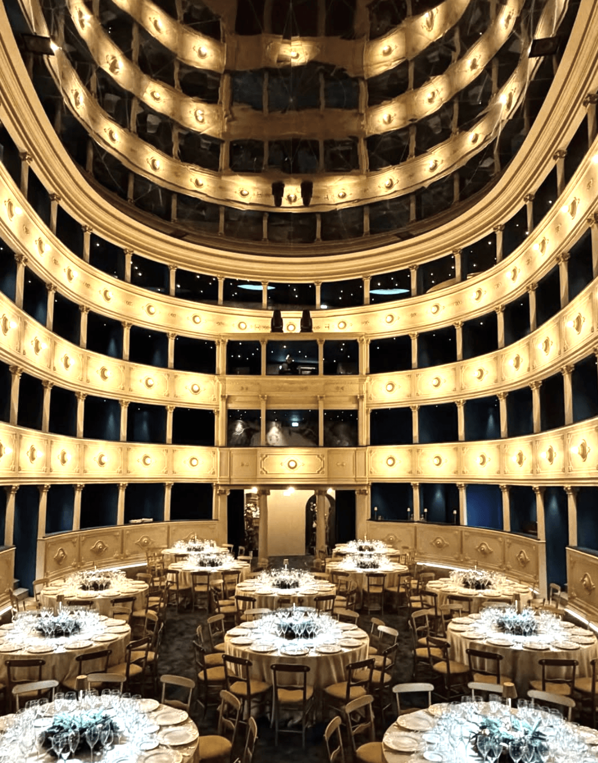 Tavoli tondi allestiti in un teatro da luxury catering, per una cena di gala