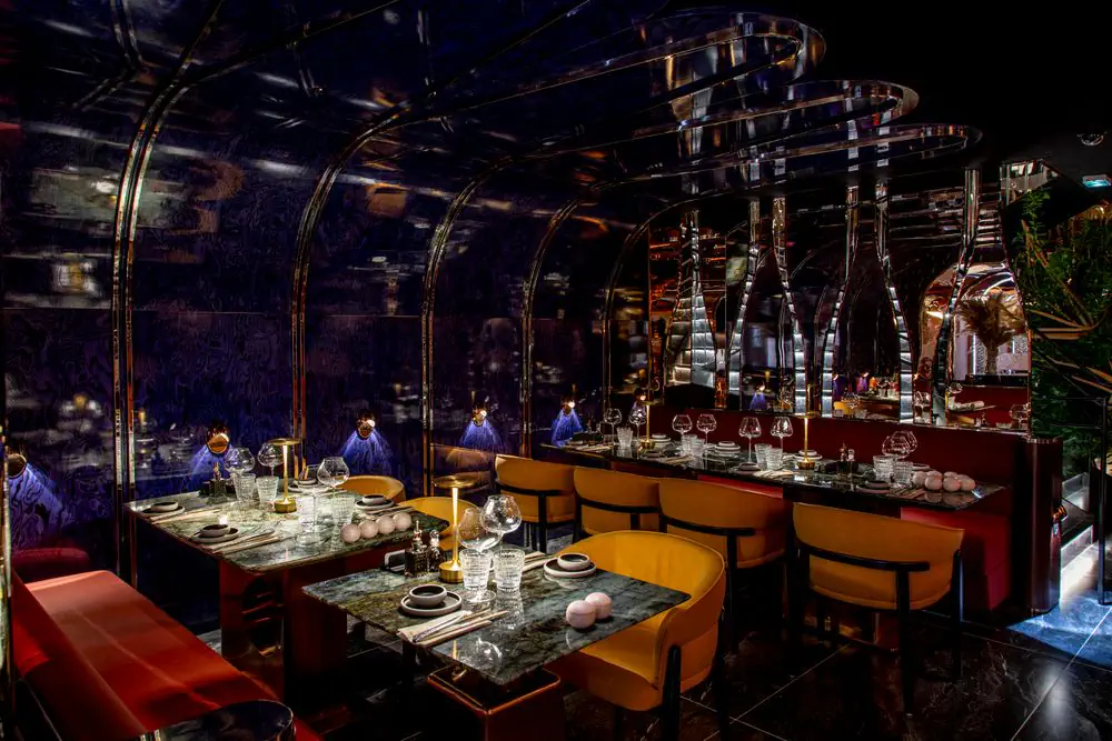 Lounge with mirrored vaults, ochre armchairs and green marble tables
