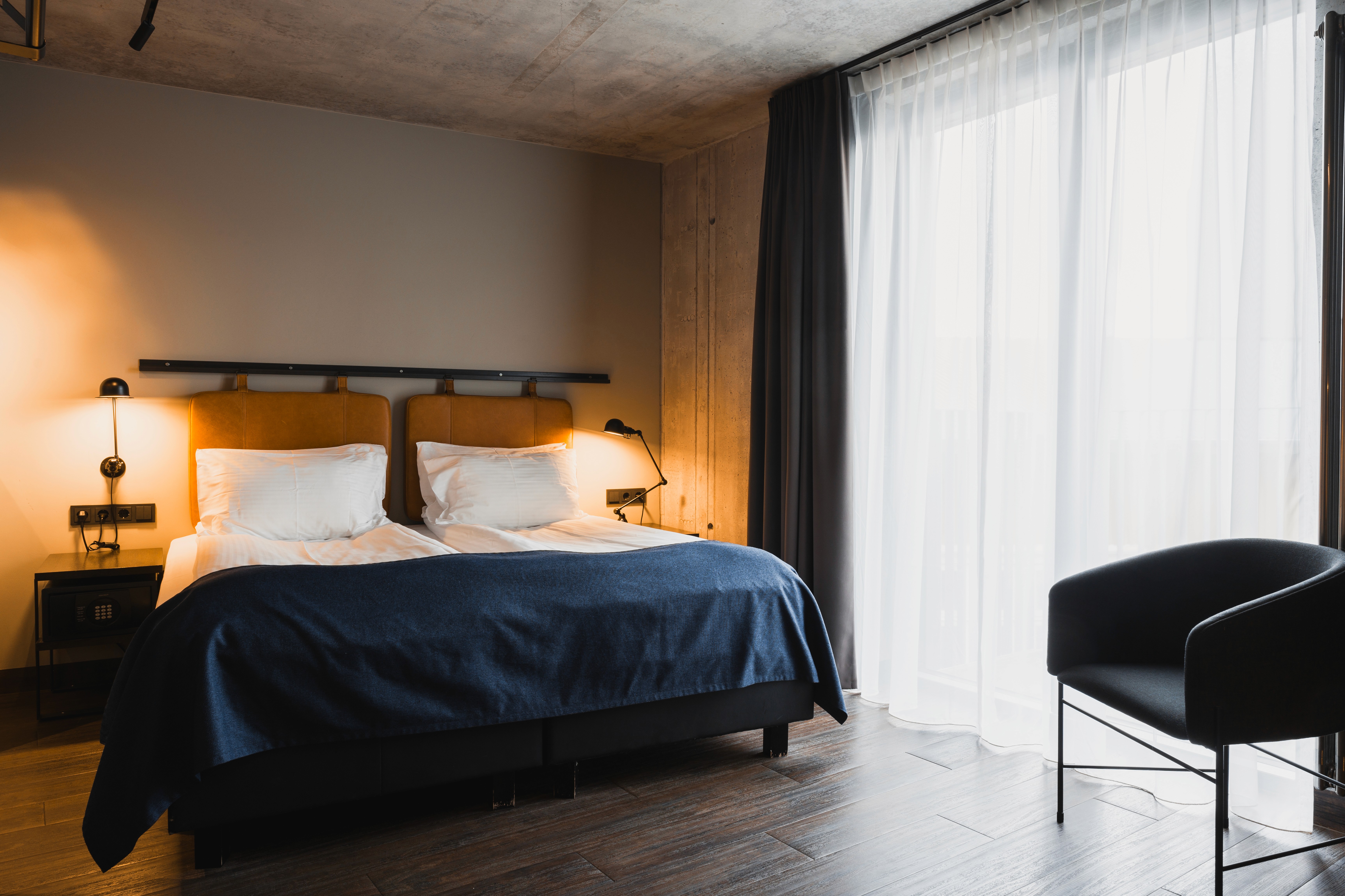 Modern guest room at Exeter Hotel in Reykjavík with two single beds, floor-to-ceiling windows, and minimalist design.