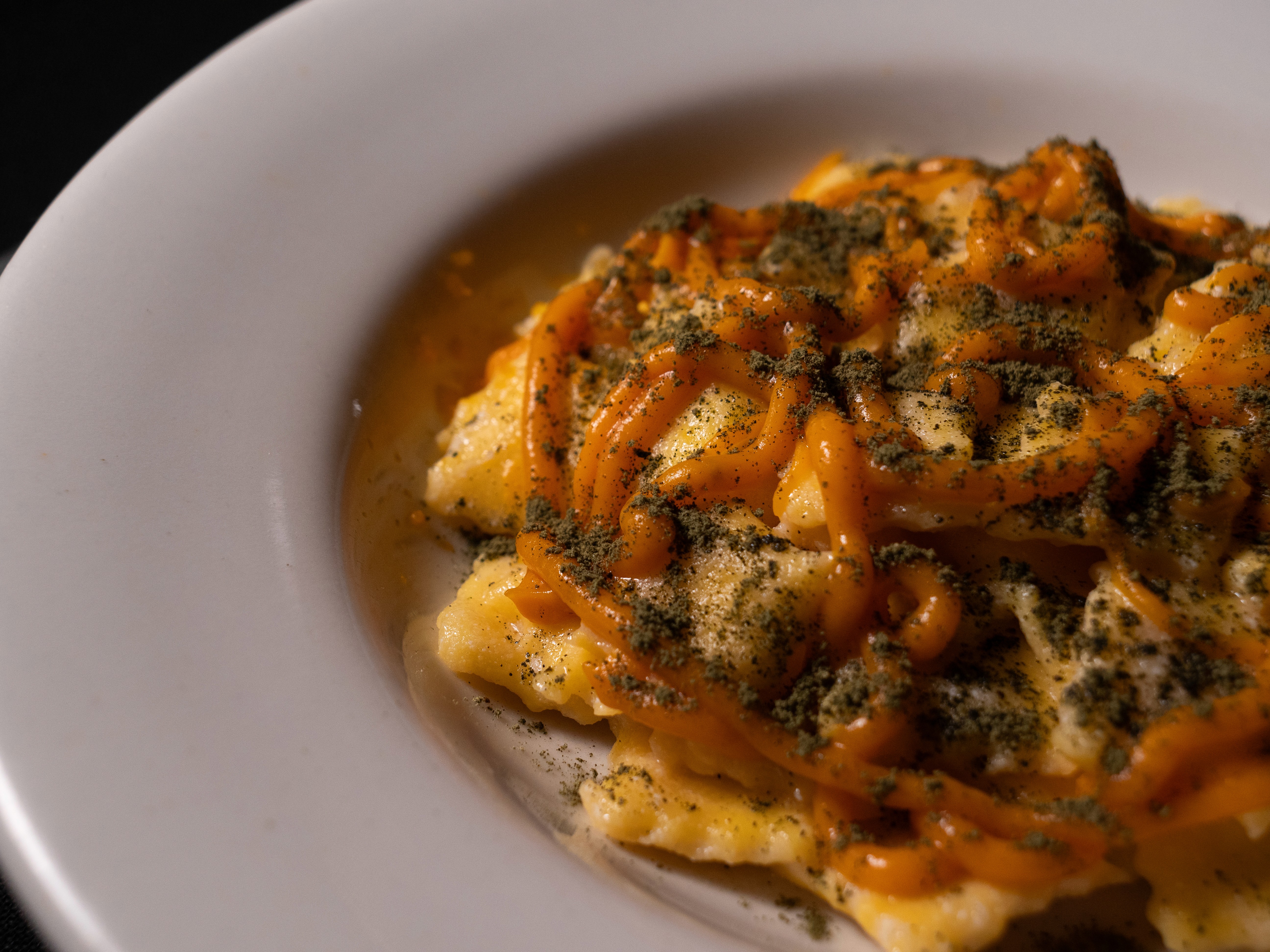 White plate with roasted chicken served in a golden sauce with herbs and capers, placed on a terrazzo tabletop in sunlight.
