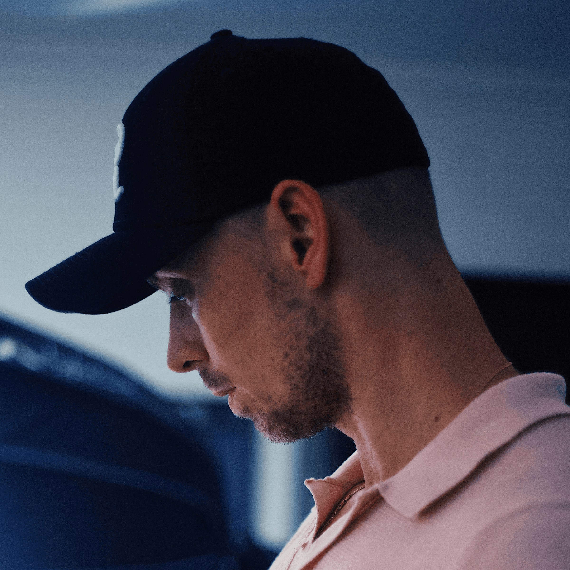 man in white polo shirt wearing black cap