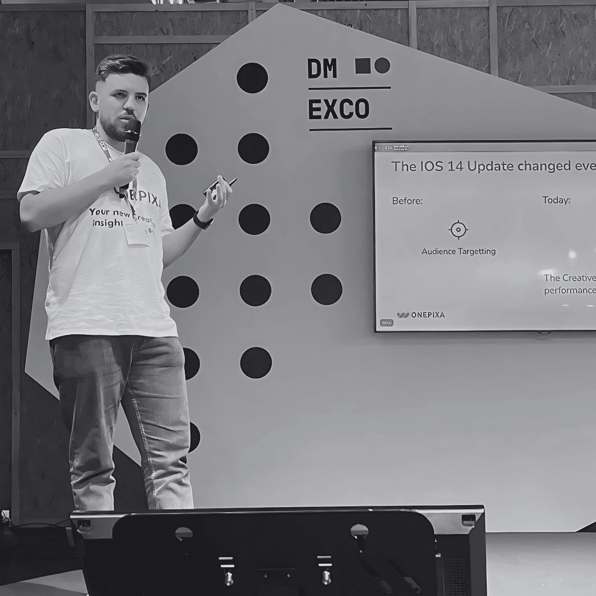 Black and white photo of two people looking at a computer screen with papers on wall