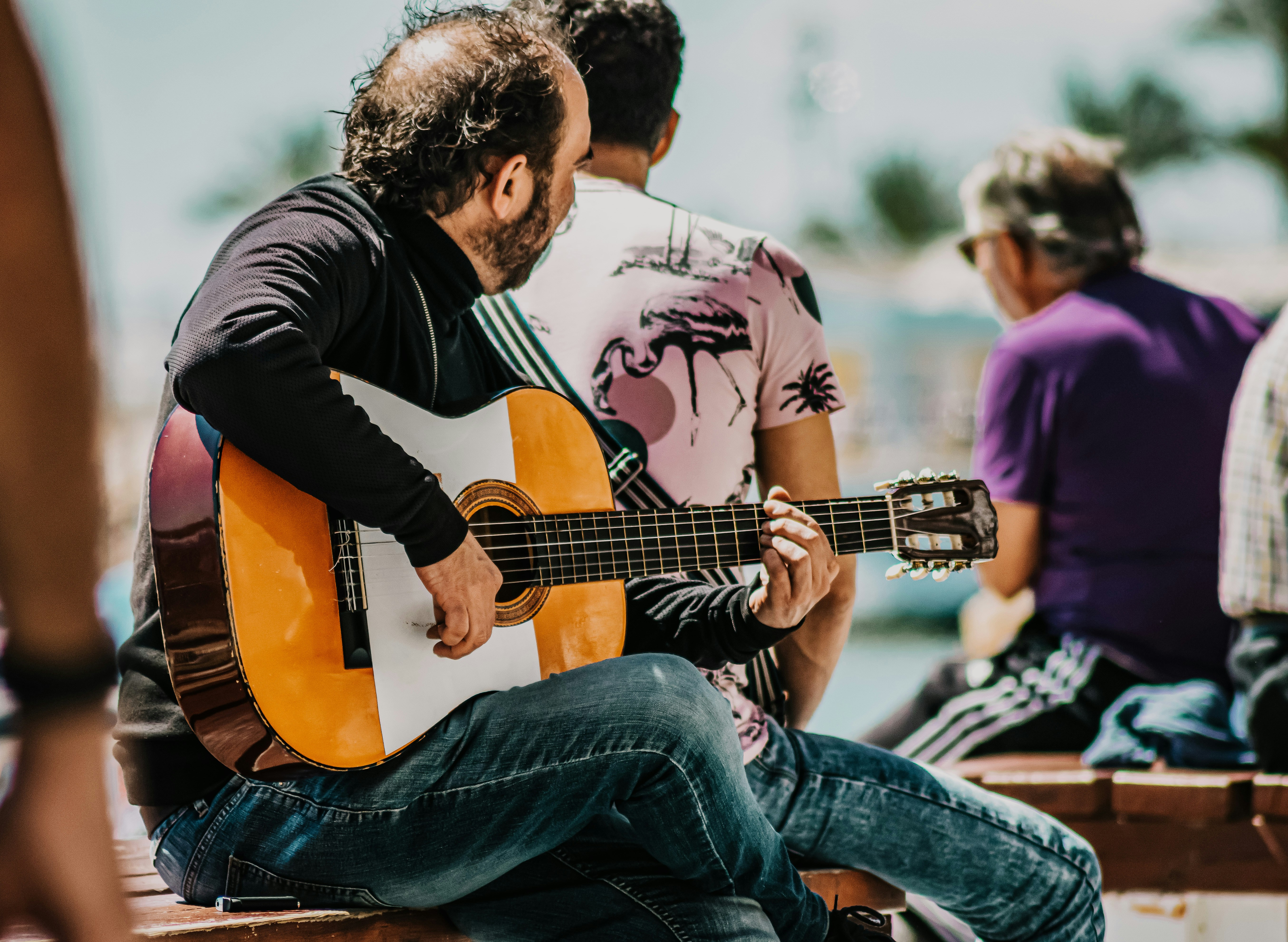 man in black long sleeve shirt playing acoustic guitar