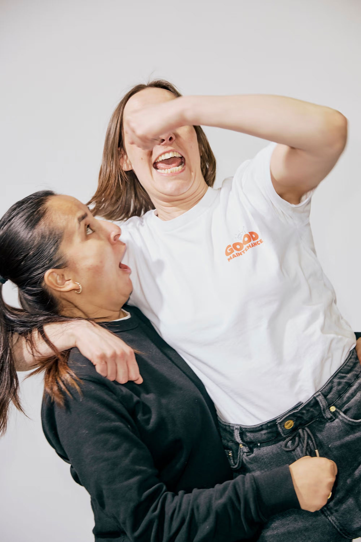 Two team members joking and laughing during a photoshoot.