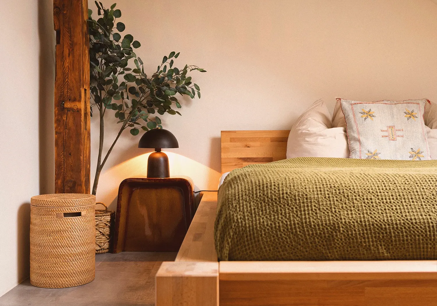 Loft N°3 • wooden bed with an olive-green throw, a mushroom lamp and an old timber beam