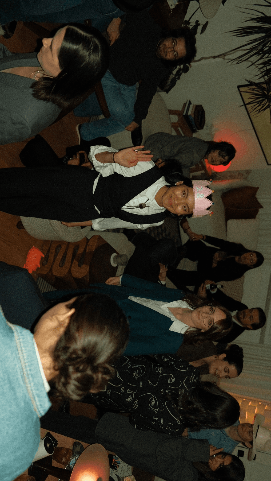 A crowded event scene with people mingling and socializing in a dimly lit atmosphere.