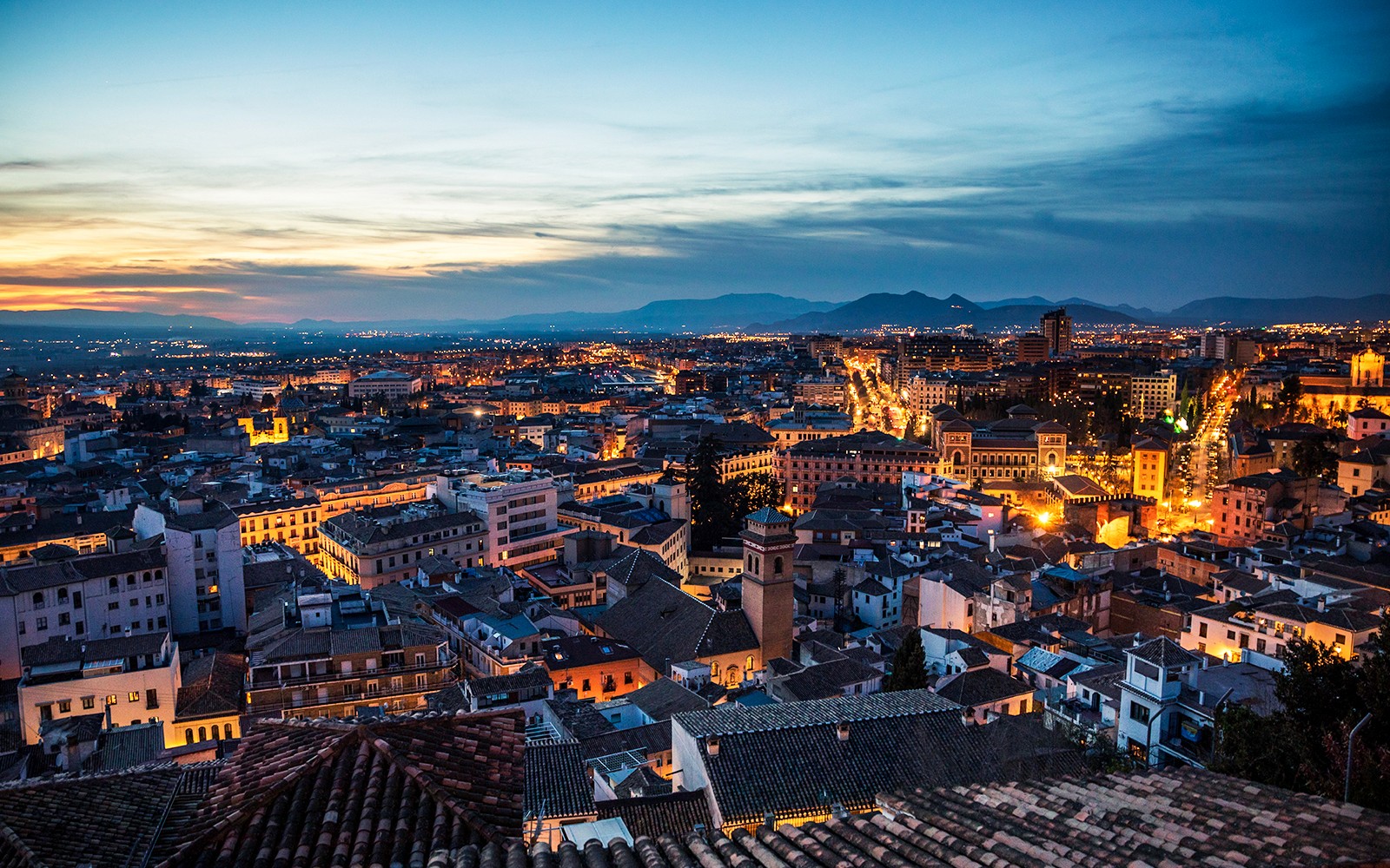Granada cityscape at dusk with illuminated streets in the Albaicín district.
