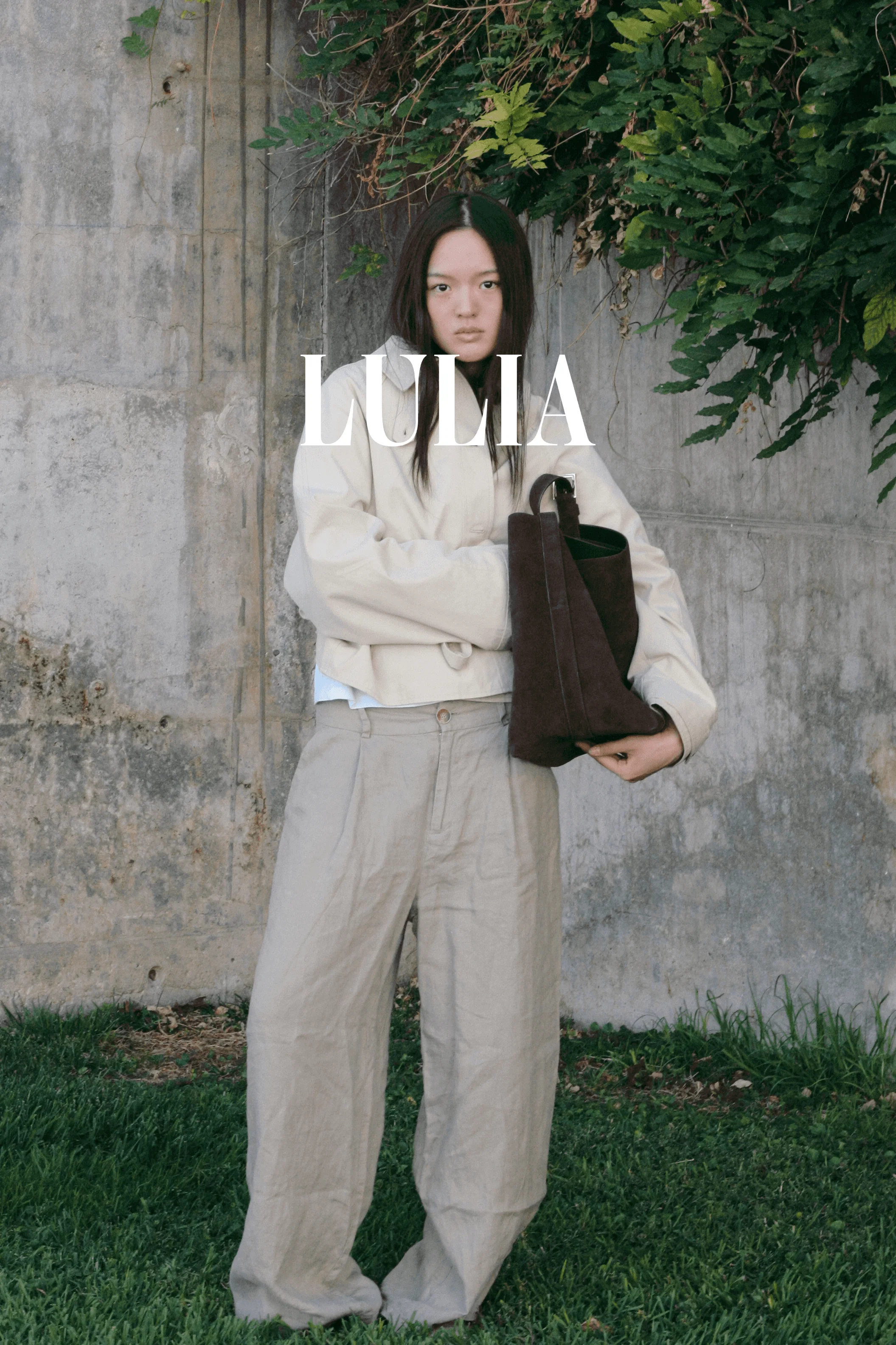 Modelo posando en un fondo brutalista naturalista con un bolso de la marca de bolsos artesanales Lulia Spain