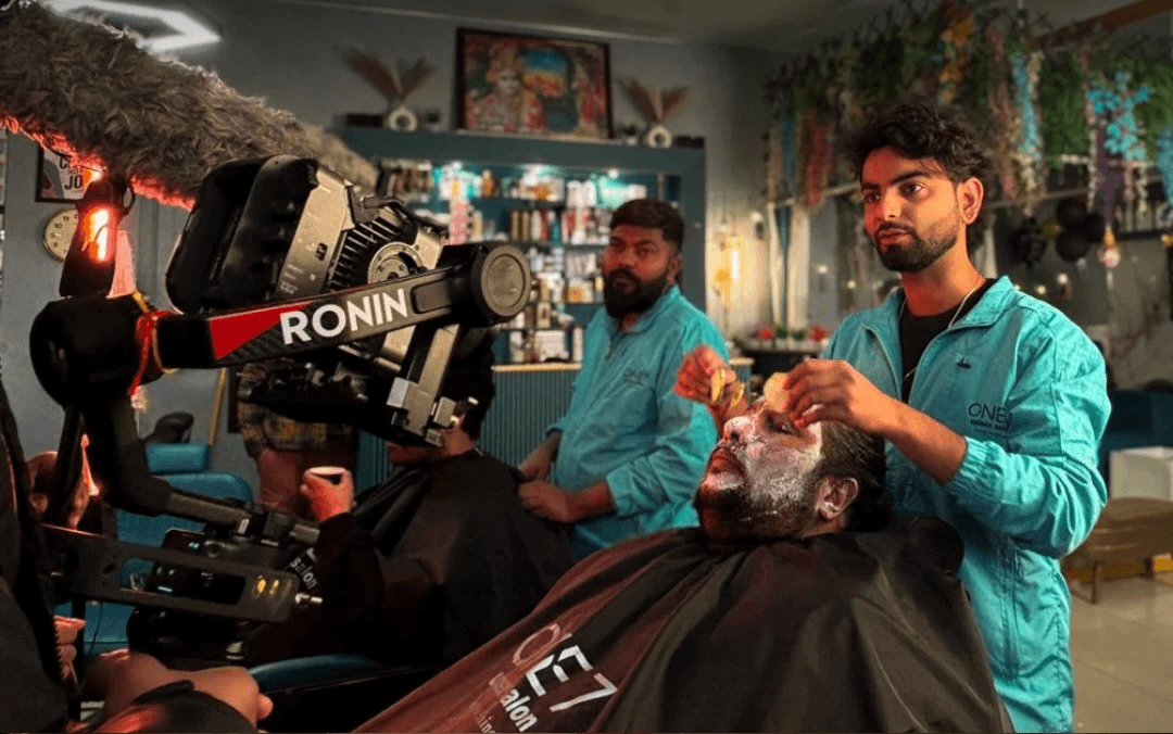 Portrait of a woman in a red turtleneck under a white pendant lamp against a blue background.