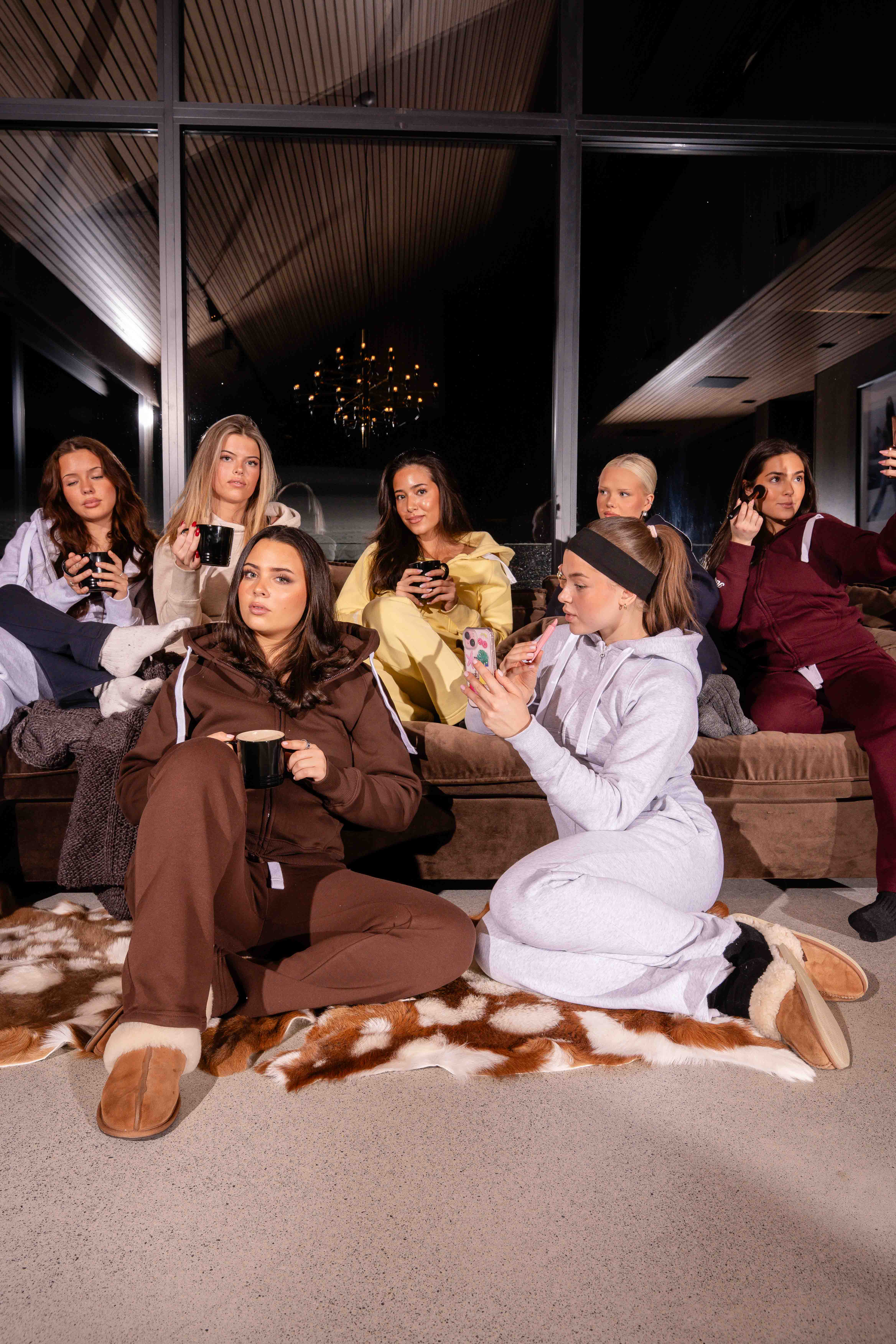 Seven young girls wearing different colored slacks inside a cabin at night