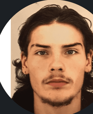 Close-up portrait of a freckled woman with soft pink hair and star earring, natural light, white tank top.