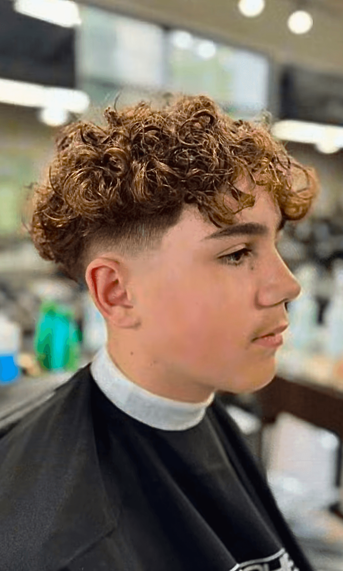 Curly perm with textured fade haircut for men, highlighting natural volume and vibrant style by Courtney Palmore.