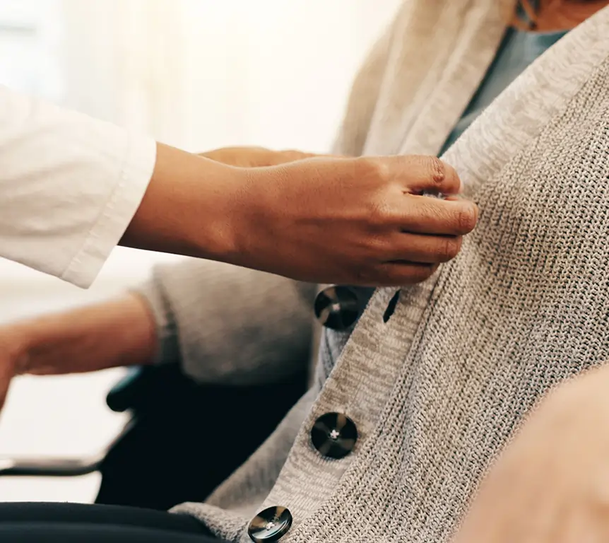 Caregiver helping a senior with Parkinson's get dressed at home