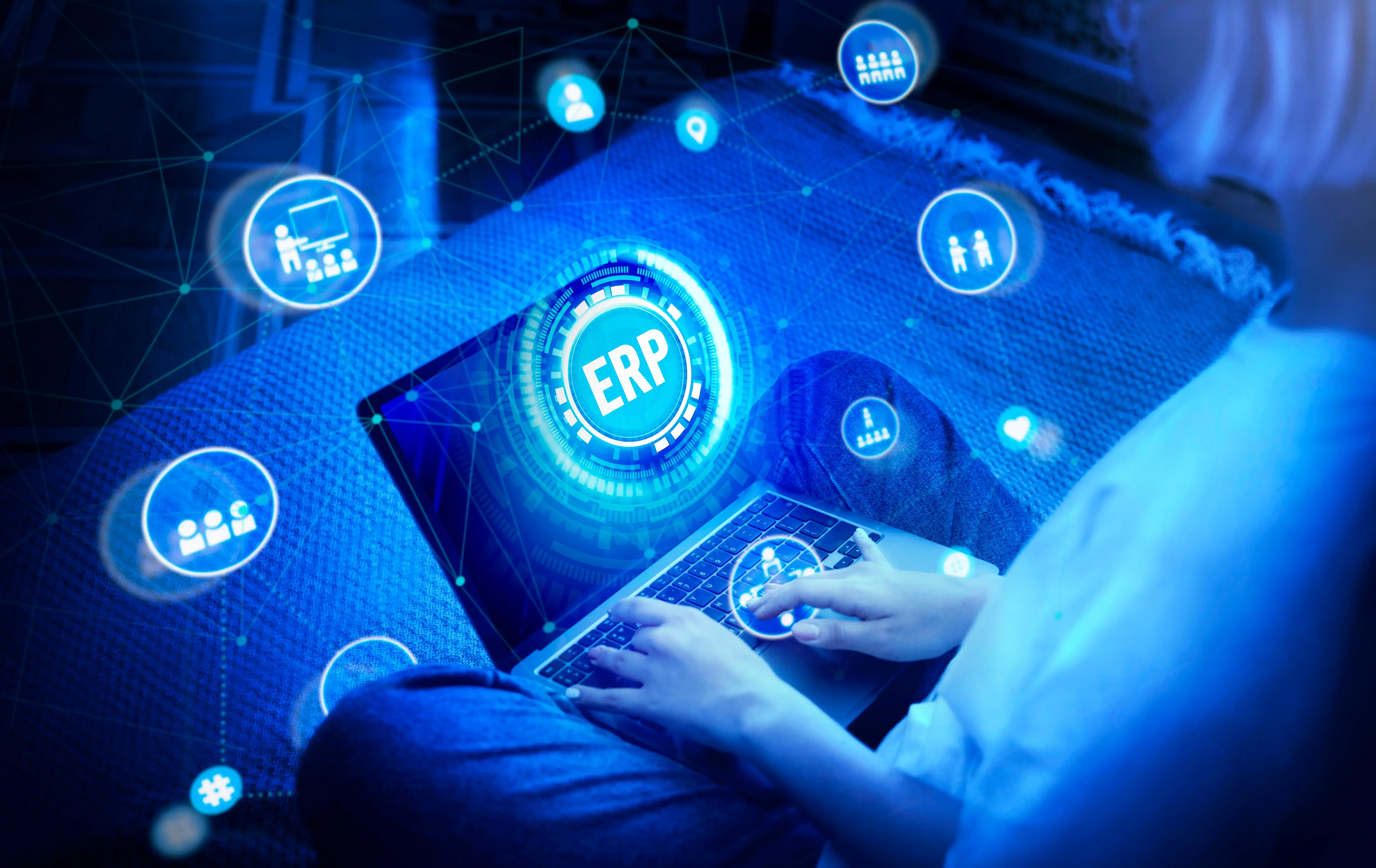 Person using a laptop with a digital overlay illustrating an ERP system, surrounded by connected icons representing data, users, and business processes.