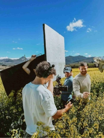 Film crew standing in a field of yellow flowers
