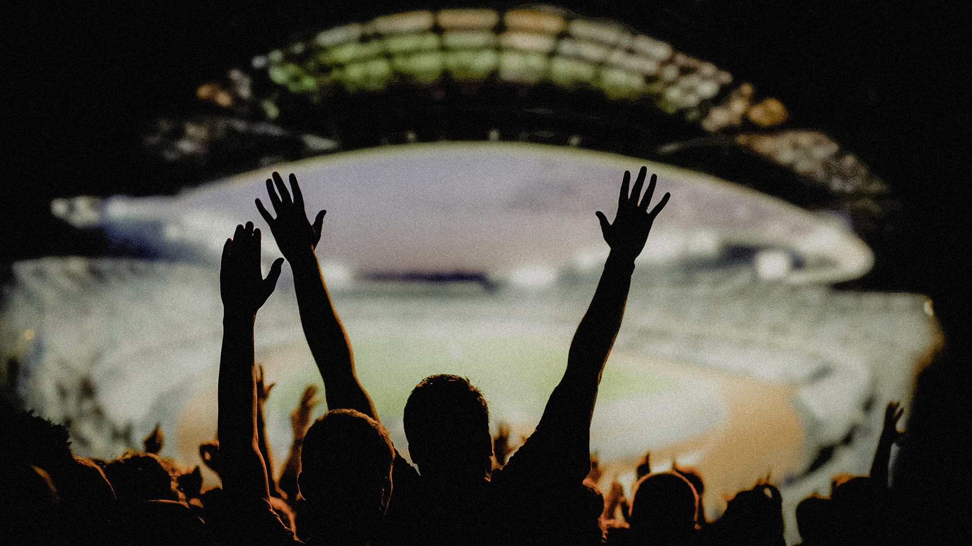 A grainy dark photo of a bunch of people celebrating in a baseball stadium.