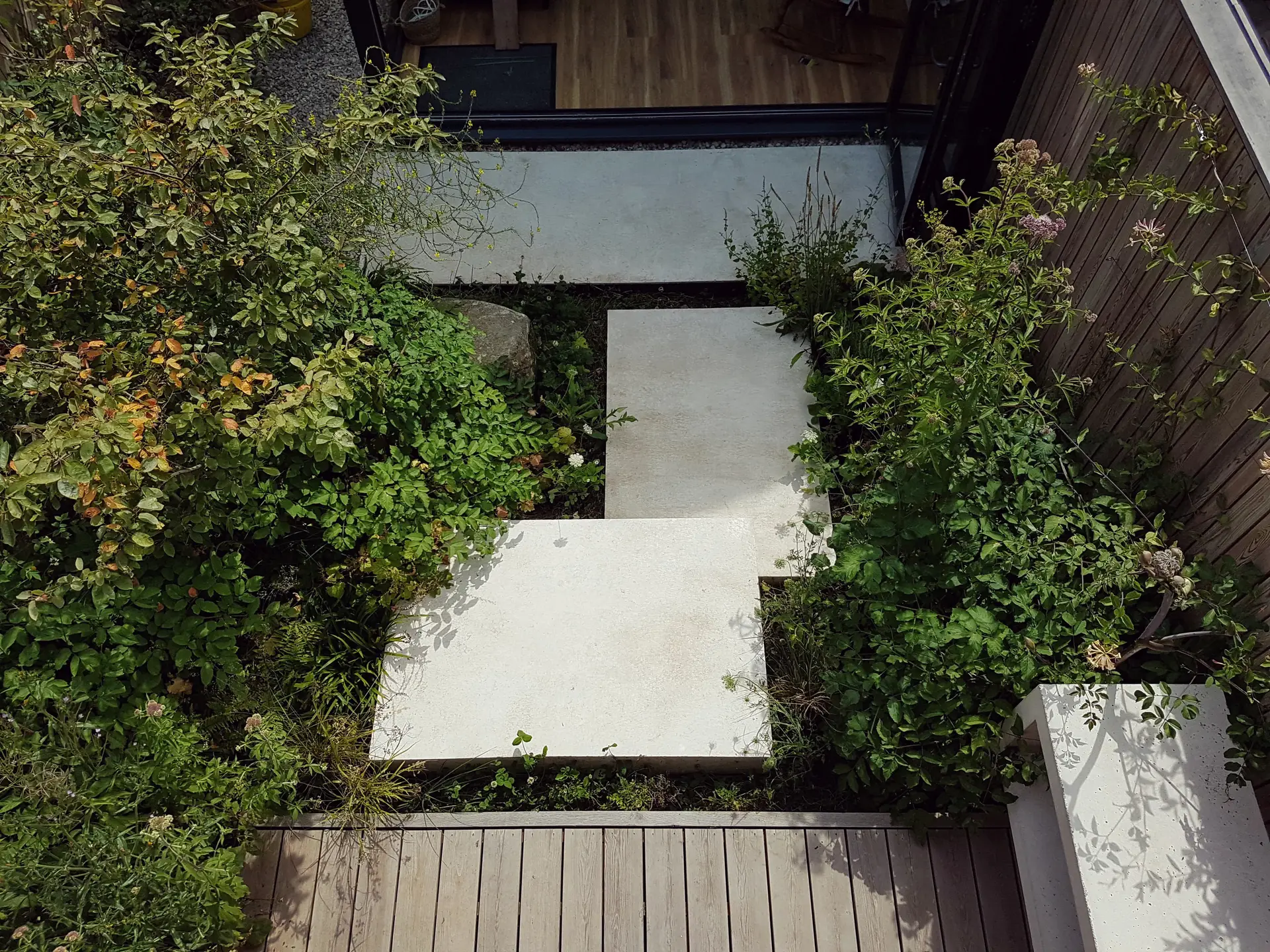 Aerial view of a modern garden path, surrounded by greenery and geometric stone paving.