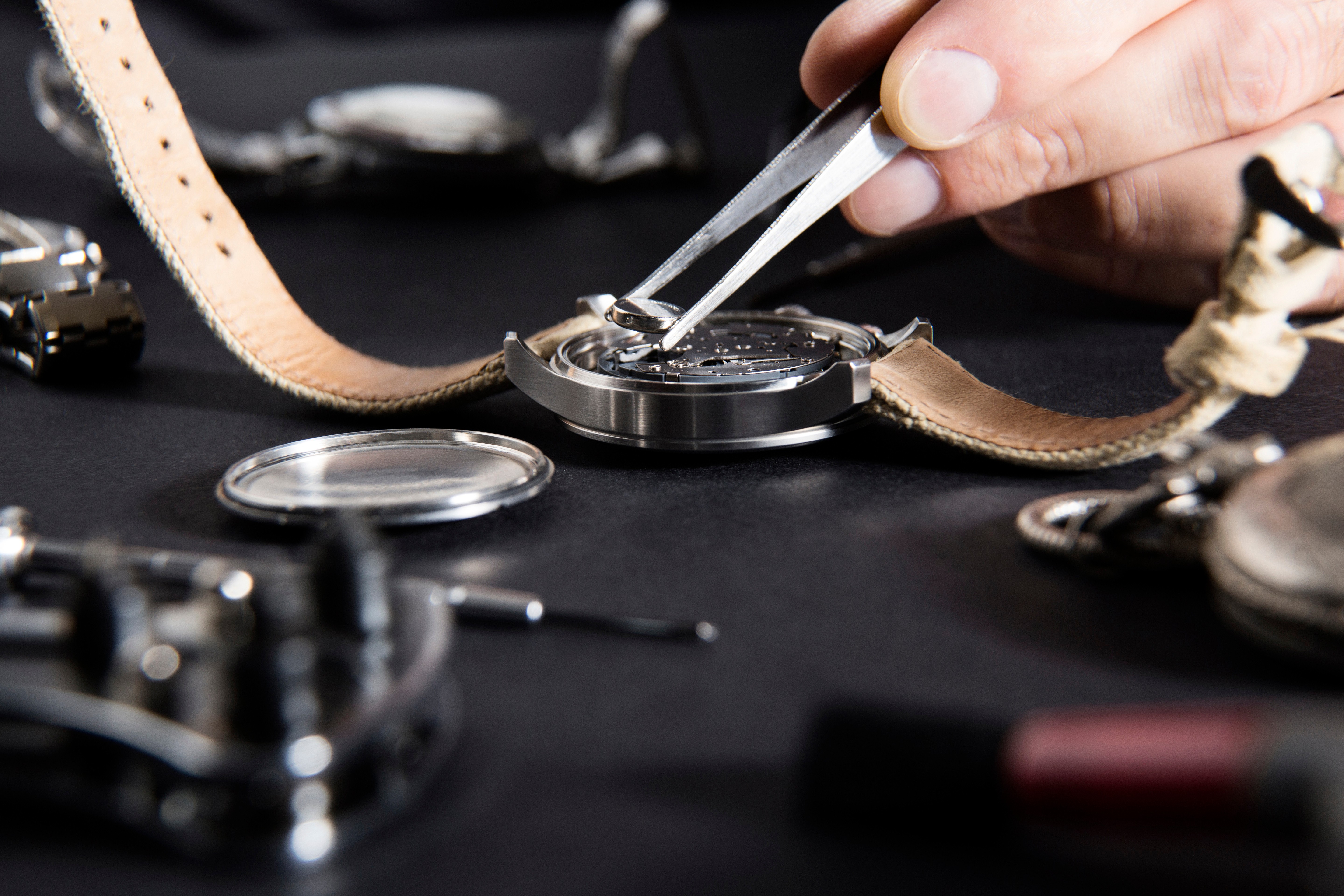 A watchmaker at a Swiss watch repair business replaces a battery